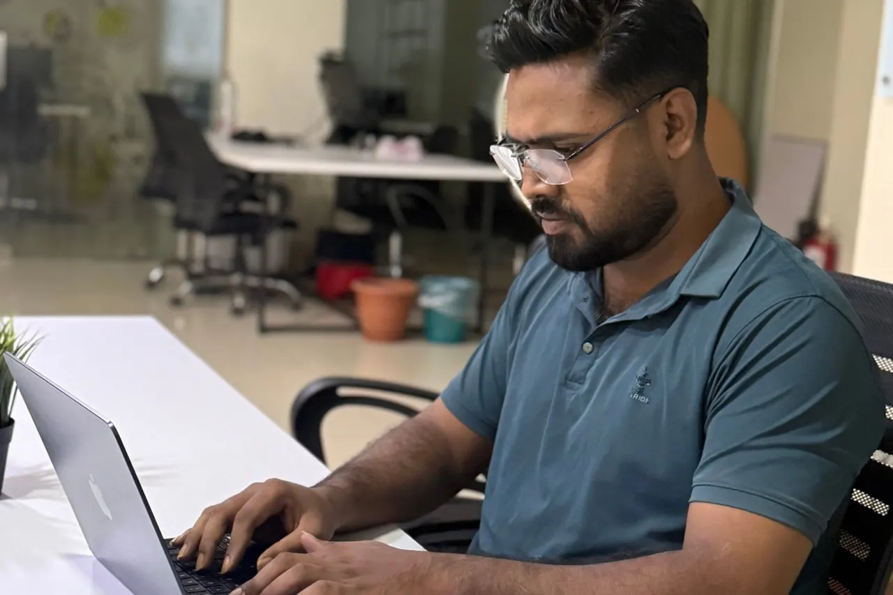 KMR Jibon typing at a white desk in an open-plan office